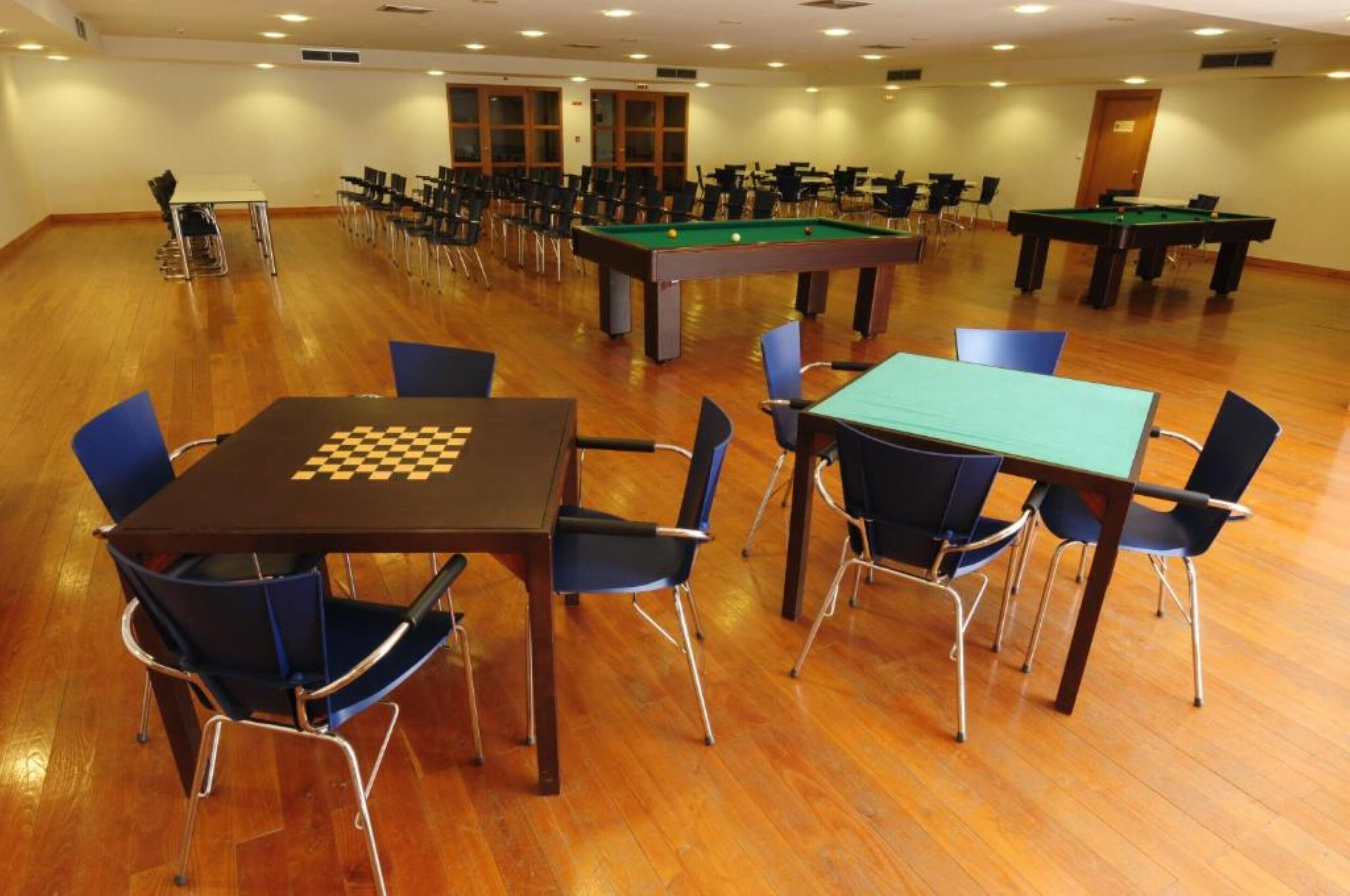 Ein Raum mit mehreren Tischen und Stühlen, einem Billardtisch und einem Snookertisch.