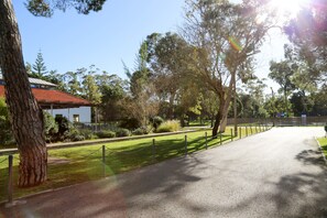 A paved pathway flanked by trees and a building with a red roof. - INATEL Caparica (Almada)