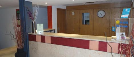 Una recepción con un reloj, un cartel del hotel y una pared de madera.