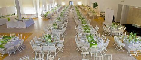Un amplio salón con filas de mesas y sillas, dispuesto para un evento formal.