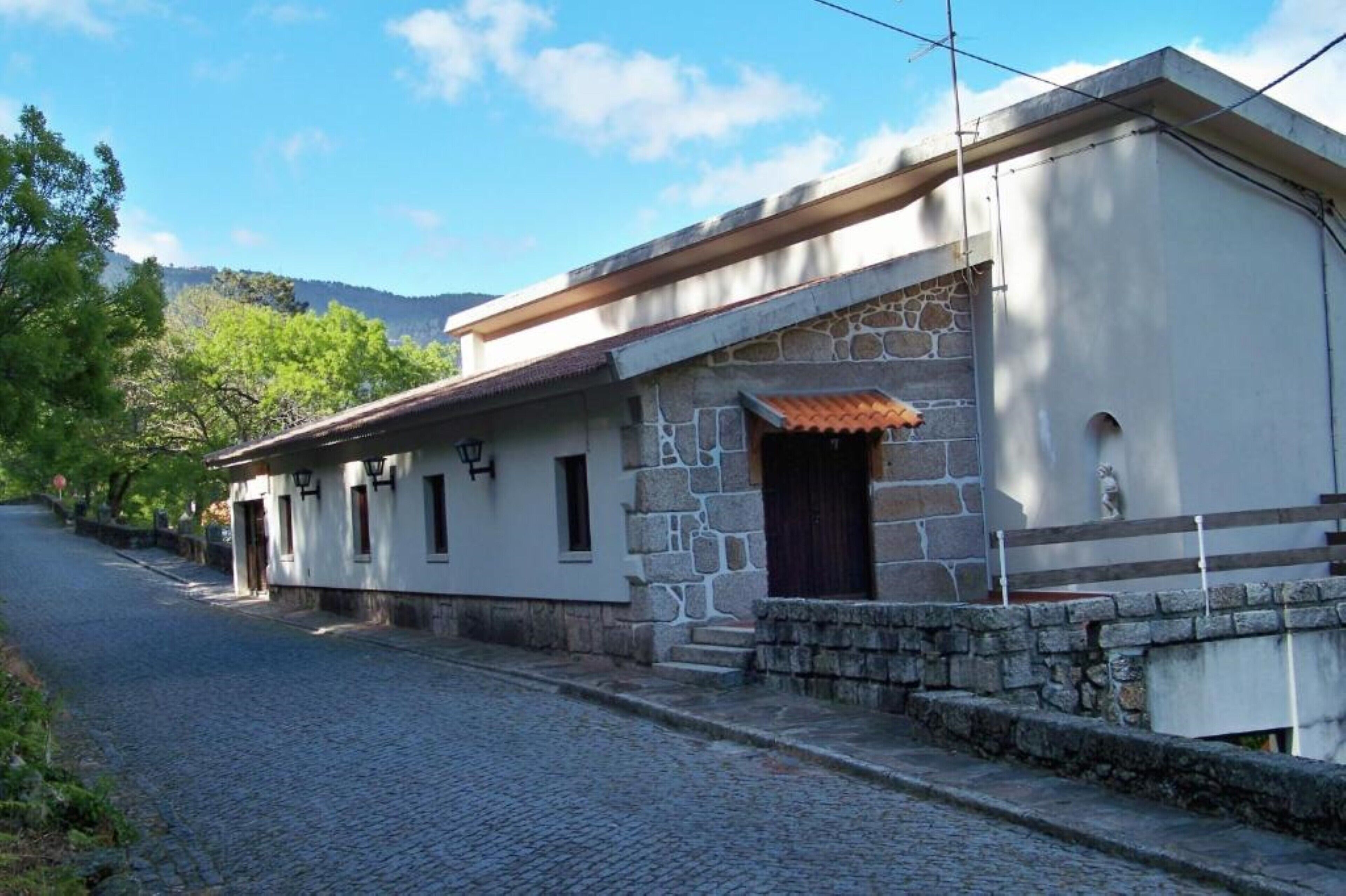 Un edificio de fachada de piedra, tejado de tejas y calle adoquinada.