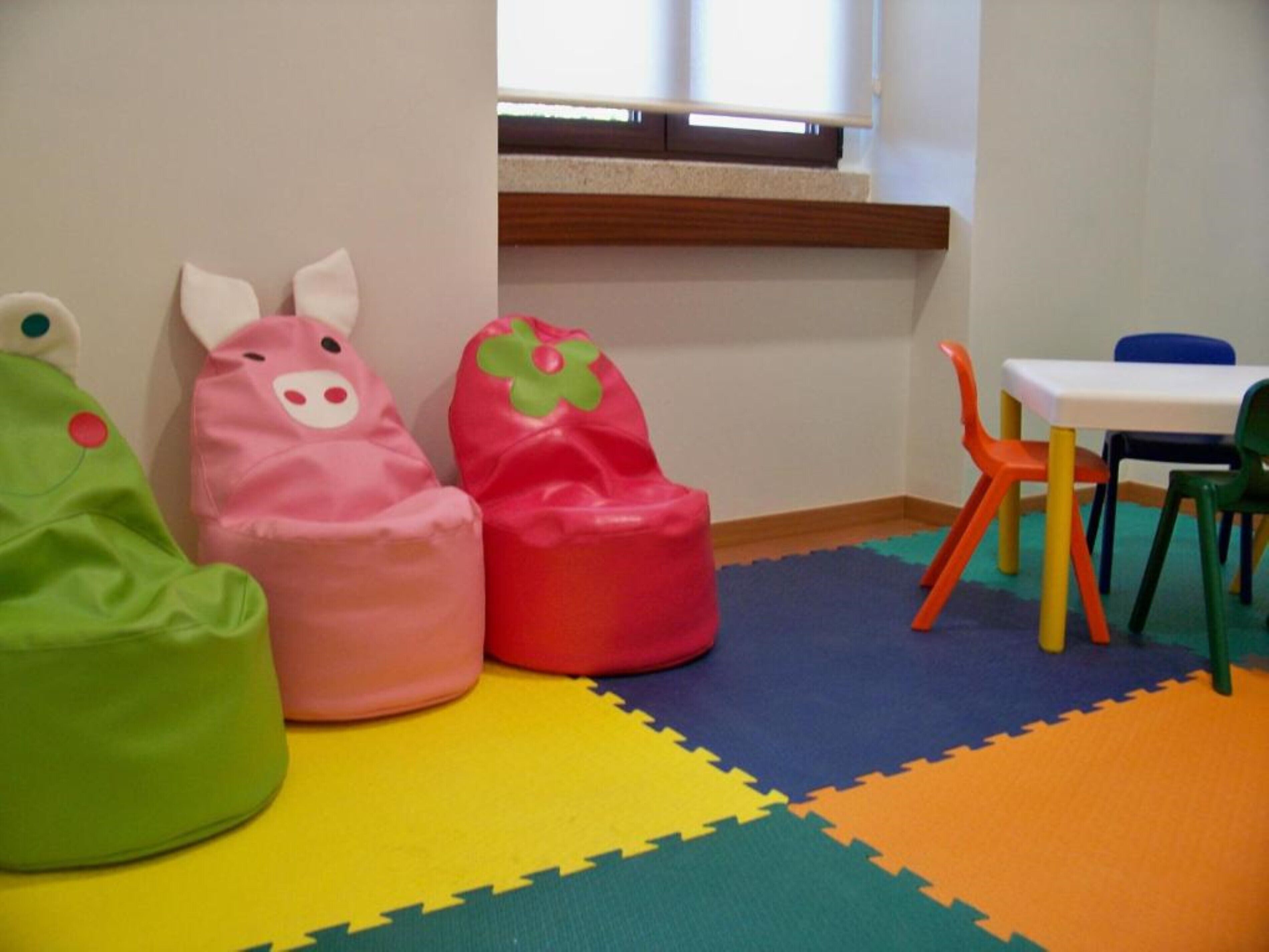 Un espace de jeux pour enfants avec des poufs colorés et une petite table entourée de chaises.