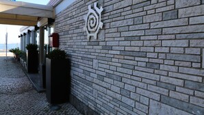 A building facade with a stone brick wall and a metal decorative element. - INATEL Oeiras (Oeiras)