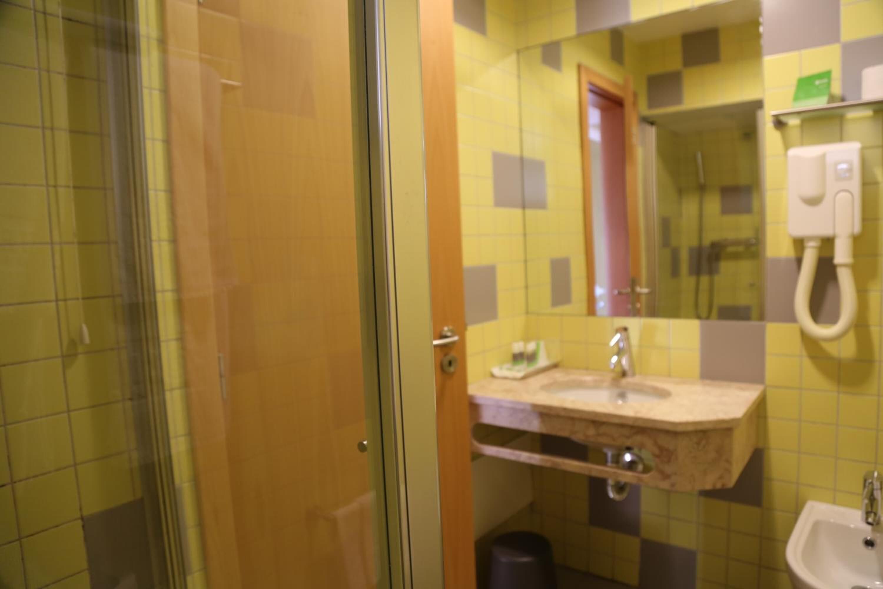 Un baño con cabina de ducha de vidrio, un lavamanos con encimera de mármol y un espejo sobre el lavamanos.