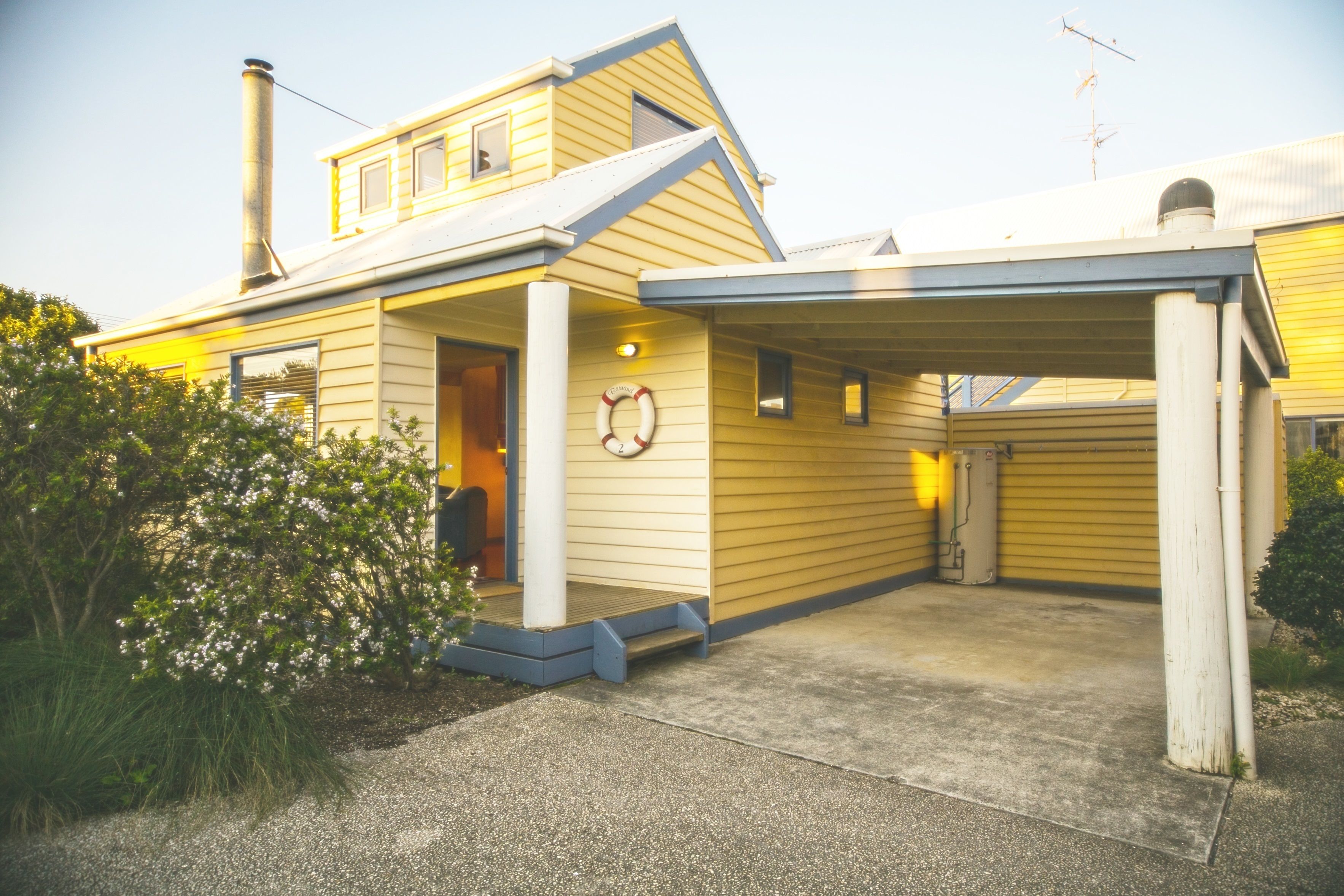 A yellow house with a covered porch and a chimney.