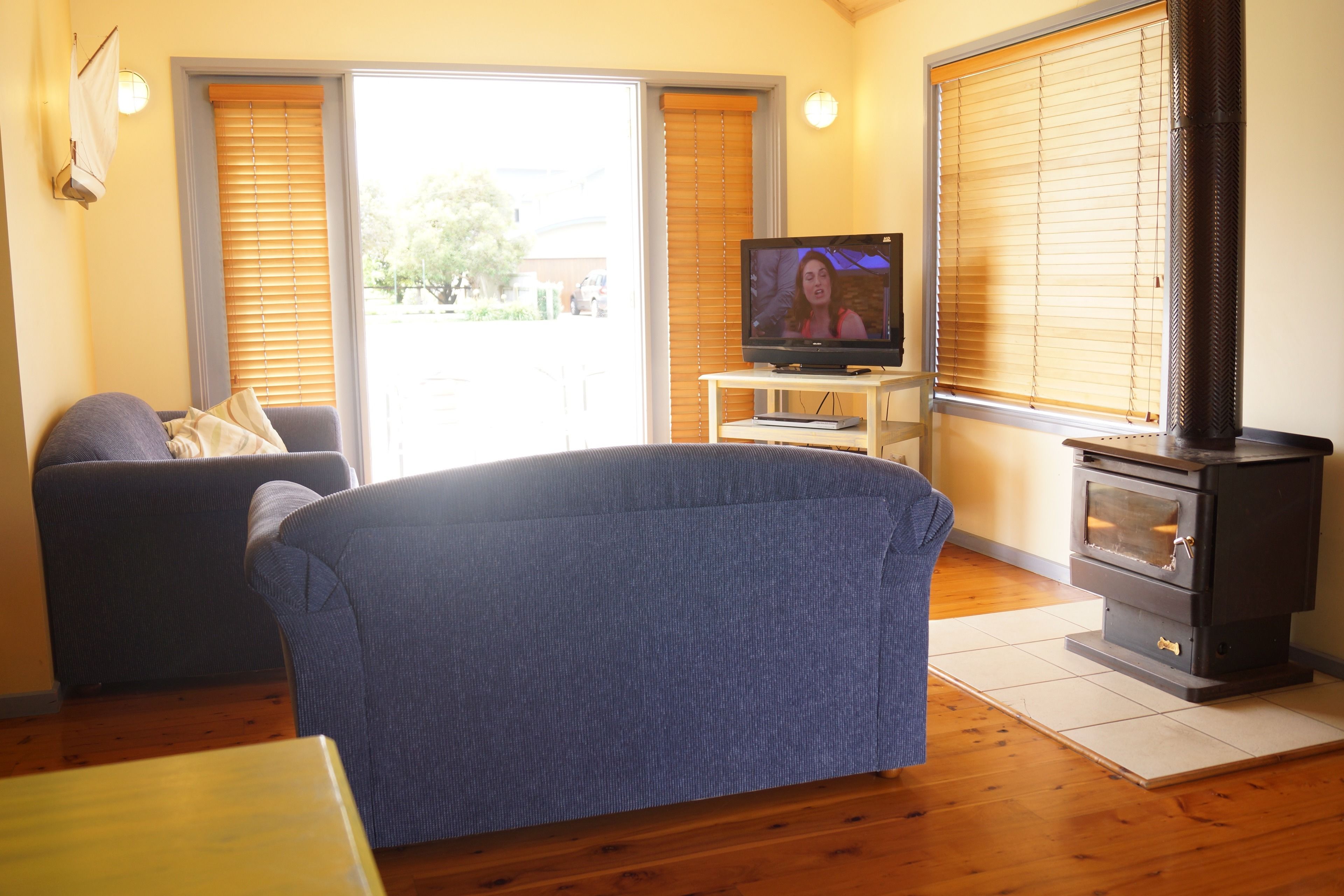 Una sala de estar con sofá, televisión y estufa de leña.