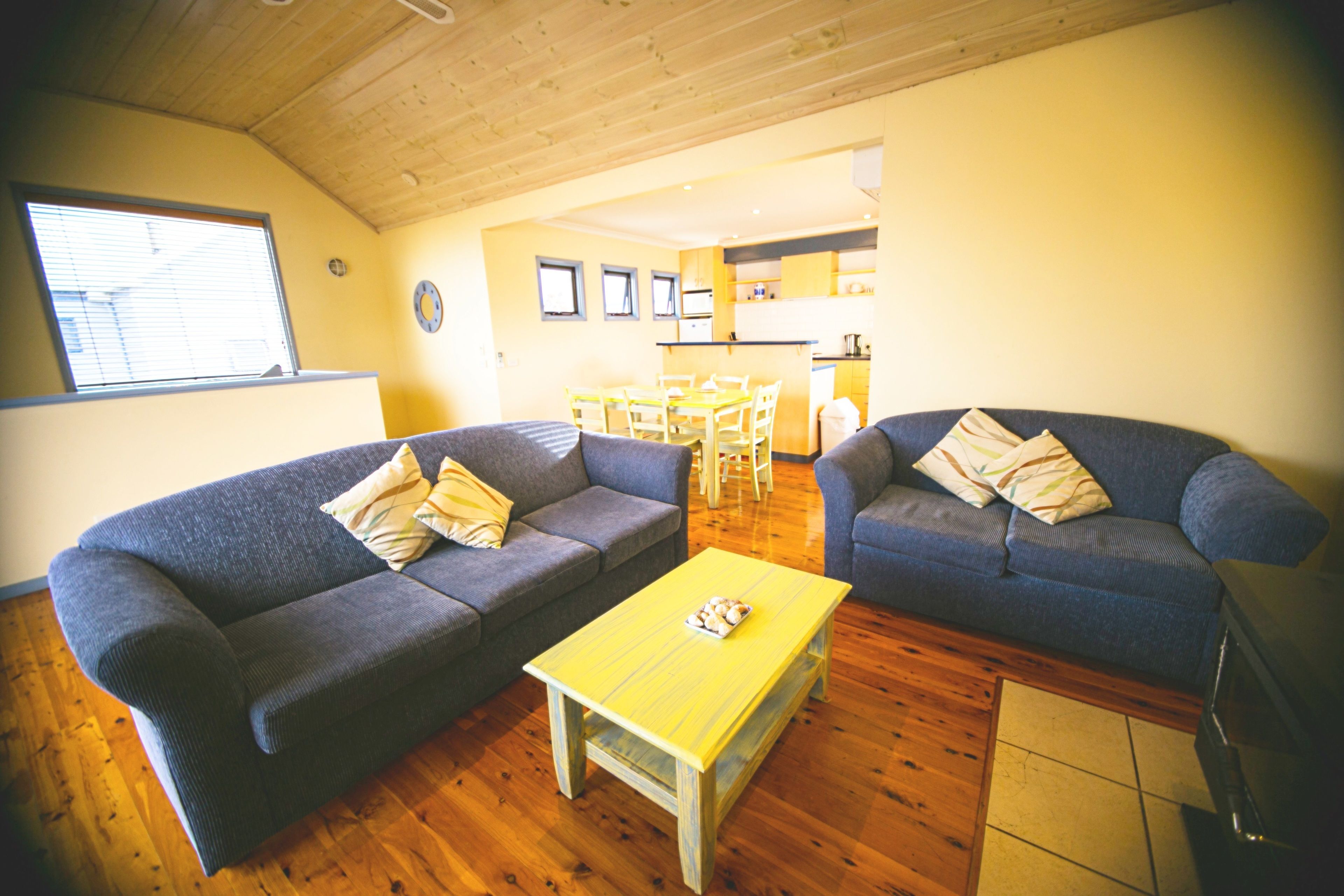 Un salon avec deux canapés, une table basse jaune et un plancher en bois.