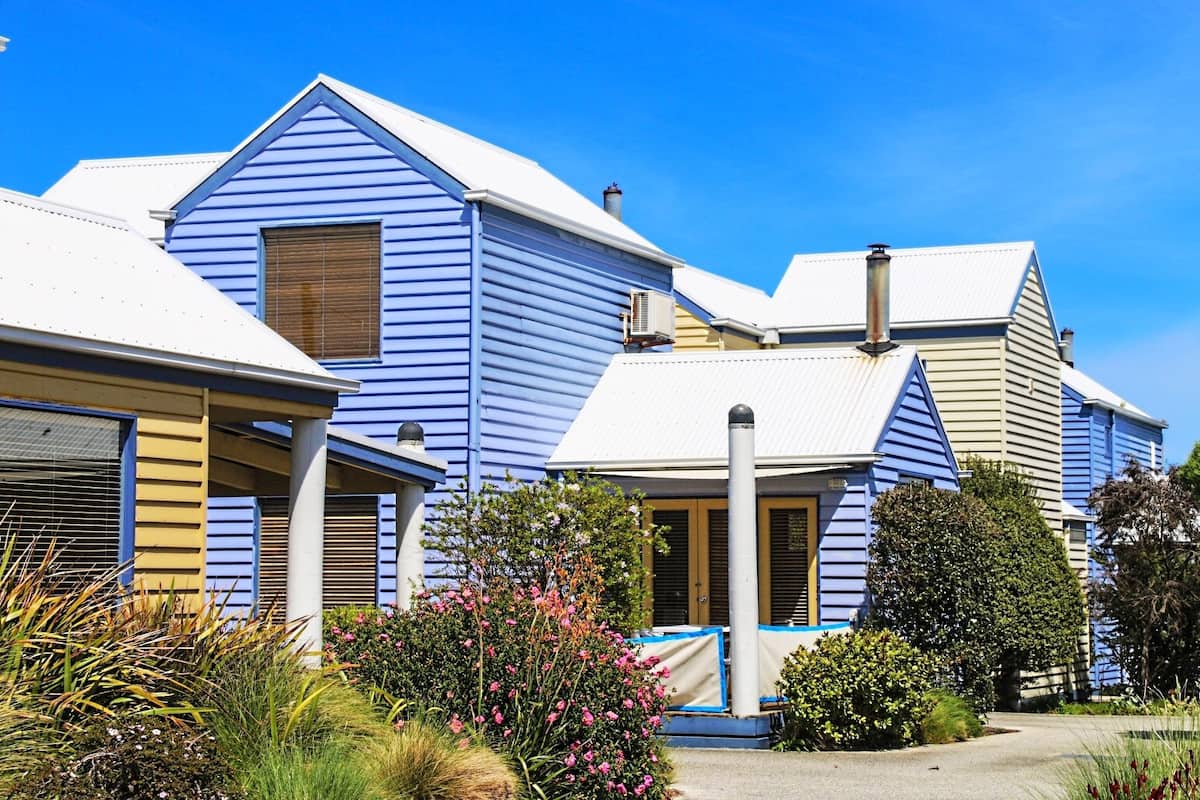 A row of blue and yellow houses with a clear sky.