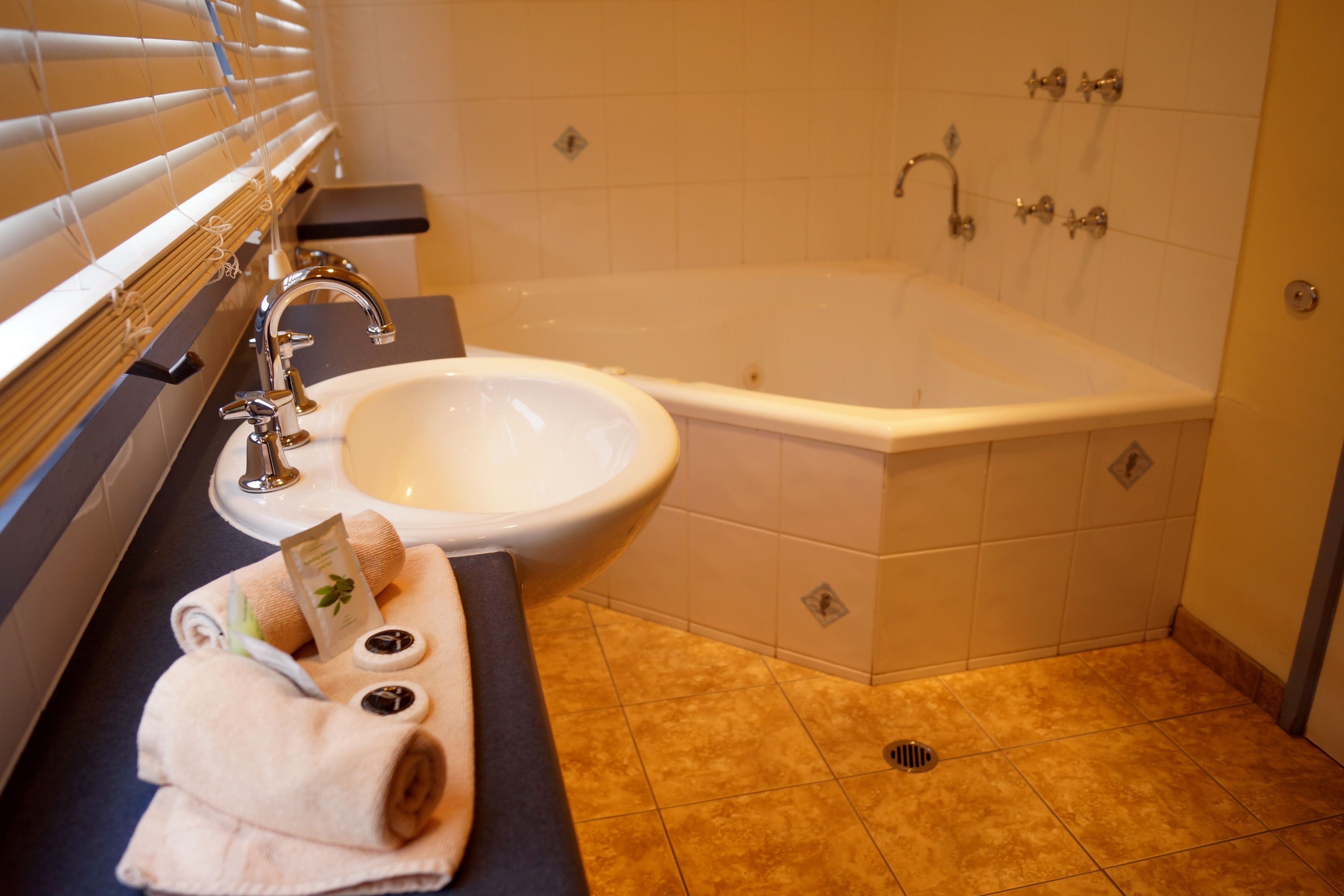 Een badkamer met een bad, wastafel en handdoekhouder.