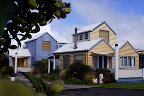 A row of two-story houses with gabled roofs, a front porch, and a small garden area. - Rayville Boat Houses (Apollo Bay)