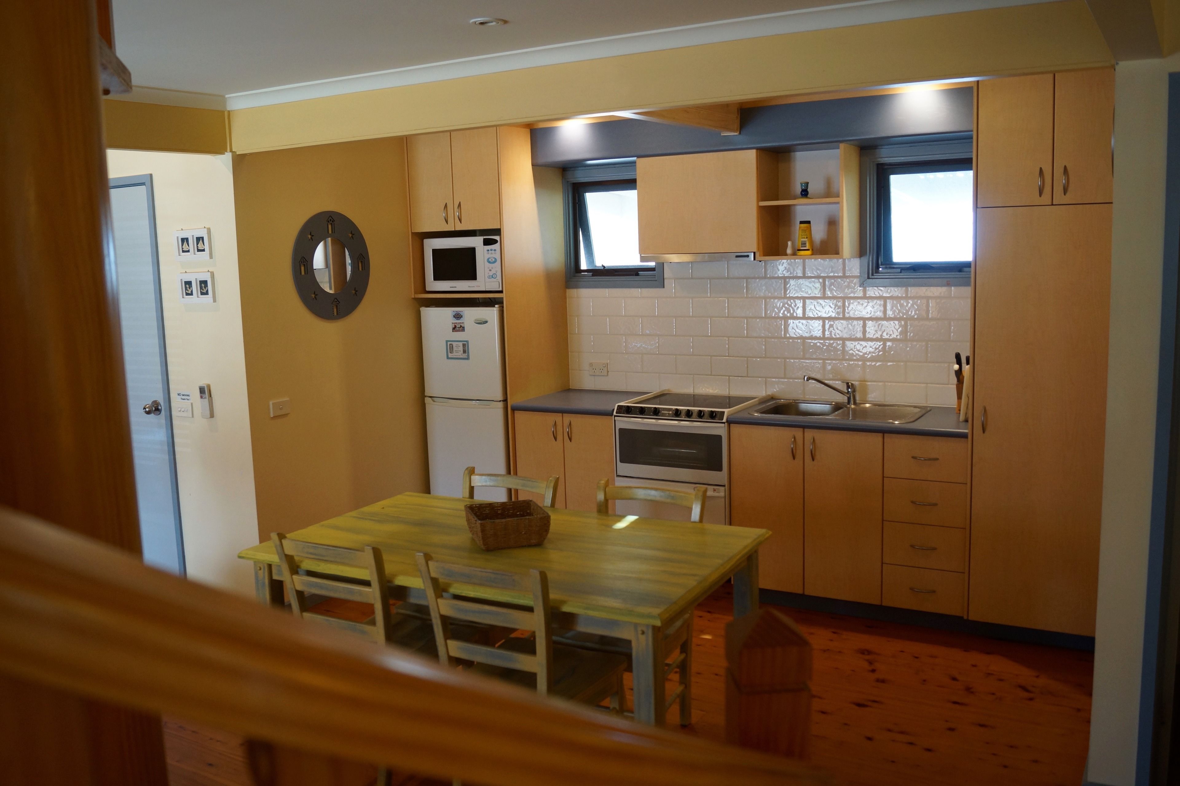 A compact kitchen with wooden cabinets, a microwave, an oven, and a sink.