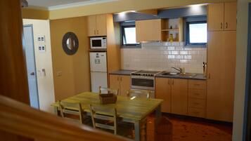 A compact kitchen with wooden cabinets, a microwave, an oven, and a sink.