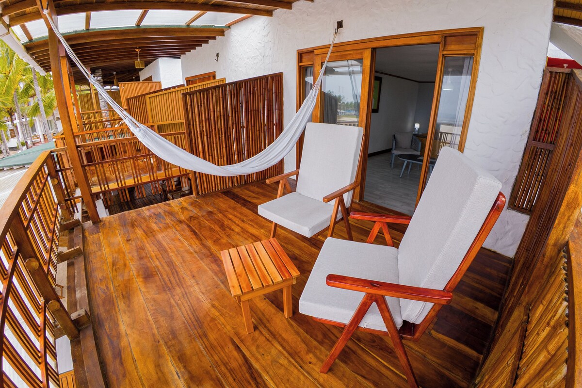 A wooden deck with two white cushioned chairs and a hammock.
