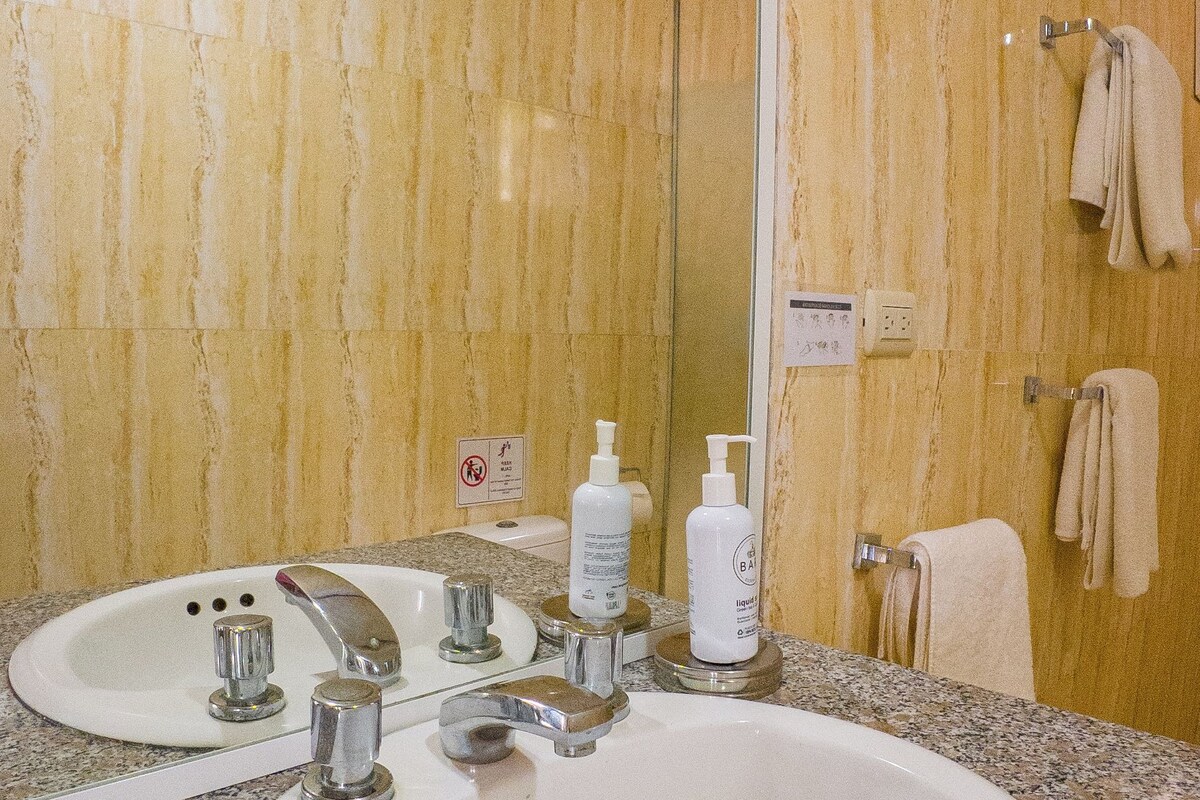 Un baño con lavamanos de encimera de granito, un espejo y un perchero para toallas.