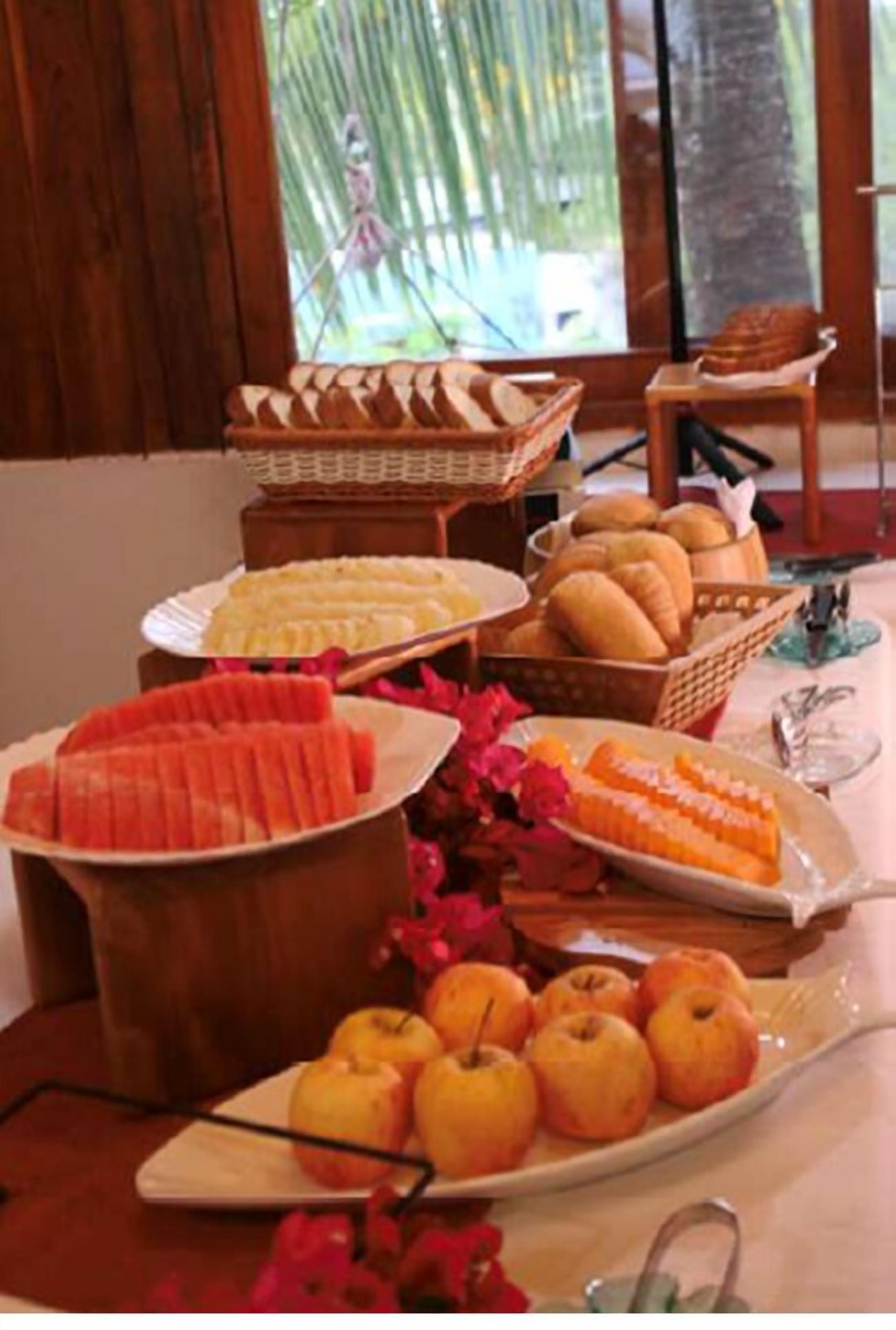 A buffet table with various food items including fruits, bread, and pastries.
