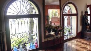 Una habitación con ventanas de arco, piso de parqué de madera y una estatua.