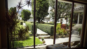 Vista de un jardín bien cuidado con setos recortados, un sendero de piedra y una variedad de plantas en macetas.