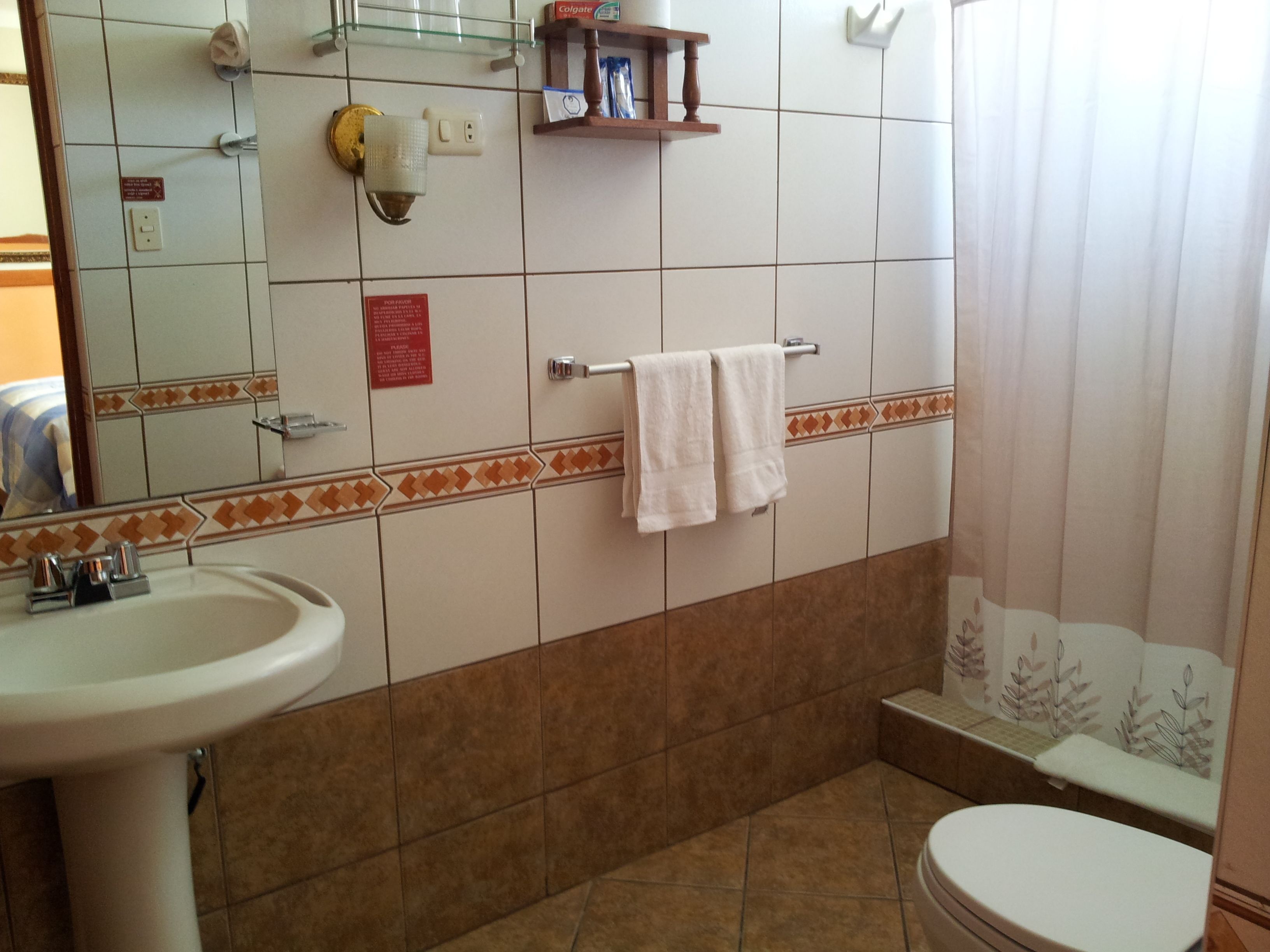 Et badeværelse med vask, spejl, håndklædetørrestativ og toilet.