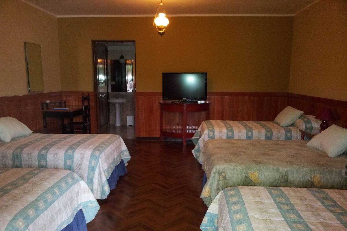 A hotel room with two beds, a television, a desk, and a bathroom.