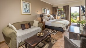 A hotel room with a sofa, a bed, a dining table, and a balcony with a view. - Algoa Guesthouse Summerstrand (Port Elizabeth)
