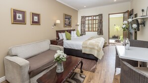 A hotel room with a bed, a sofa, a dining table, and a small table with a vase. - Algoa Guesthouse Summerstrand (Port Elizabeth)