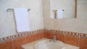 A bathroom with a sink, mirror, and towel rack. - Kuntur Inn (Puno)