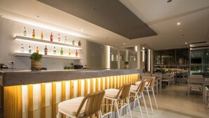 A modern bar area with a wooden slatted counter, white bar stools, and a variety of liquor bottles. - Casa Stavris (Rhodes)