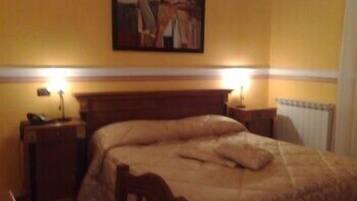 Une chambre d’hôtel avec un lit, des tables de chevet, un tableau au mur et un radiateur.