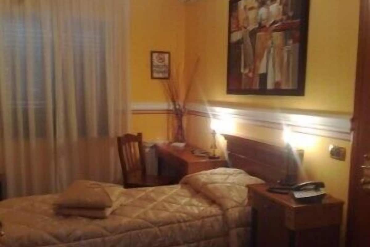 A hotel room with a bed, a nightstand, a lamp, and a painting on the wall.