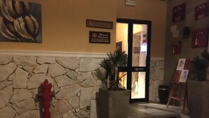 A reception area with a stone wall, a fire hydrant, a potted plant, and a sign that reads "Hotel Amadeus." - Hotel Amadeus (Caserta)