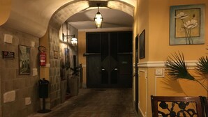 A hallway with a brick floor, a fire extinguisher, a sign for a bar, and a door at the end. - Hotel Amadeus (Caserta)