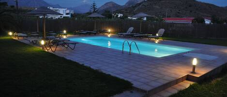 Alberca al aire libre, sombrillas en la alberca y camastros