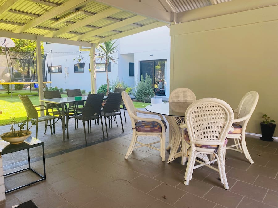 Un patio al aire libre con una mesa y sillas, un jardín pequeño y vistas a un edificio al fondo.