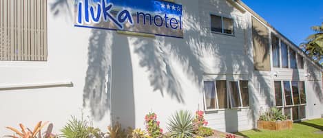 A motel with a sign reading "ilukamotel" and a well-maintained garden with various plants.