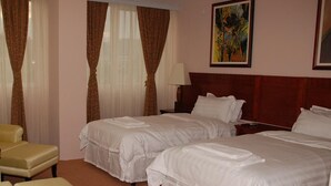 A hotel room with two beds, a chair, and a painting on the wall. - Hotel Feni (Kavadarci)