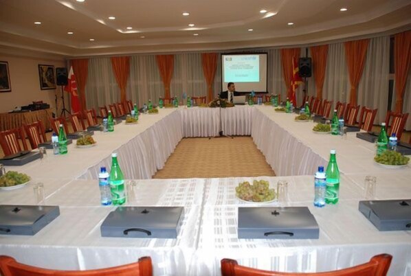 A conference room with a long table, chairs, and a presentation screen.
