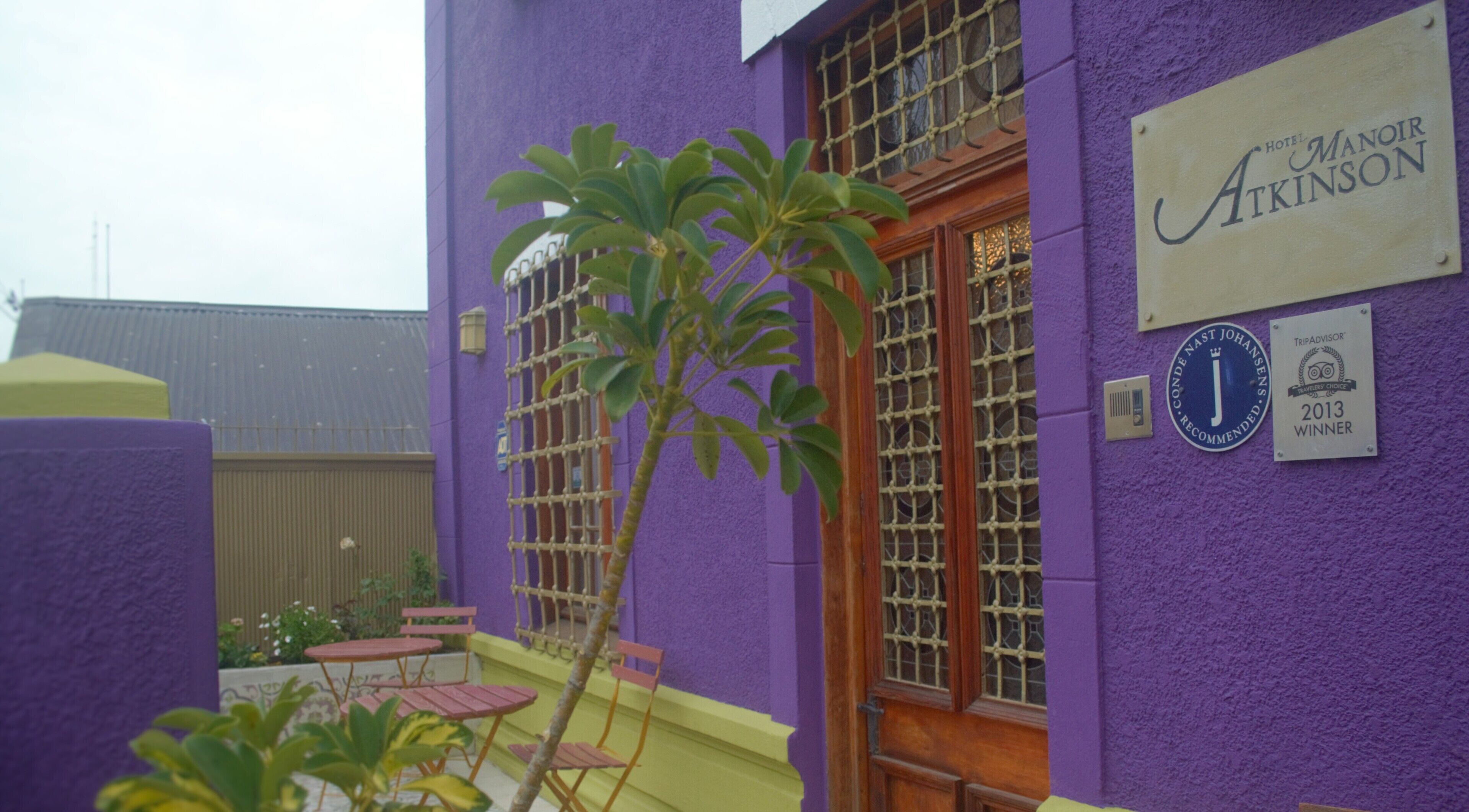 A purple building with a sign for Hotel Manoir Atkinson, a TripAdvisor 2013 winner, and a logo for Nando's.