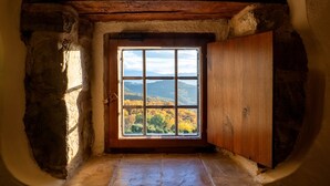 A small, rustic room with a single window offering a view of a mountainous landscape. - Castello di Petrata (Assisi)