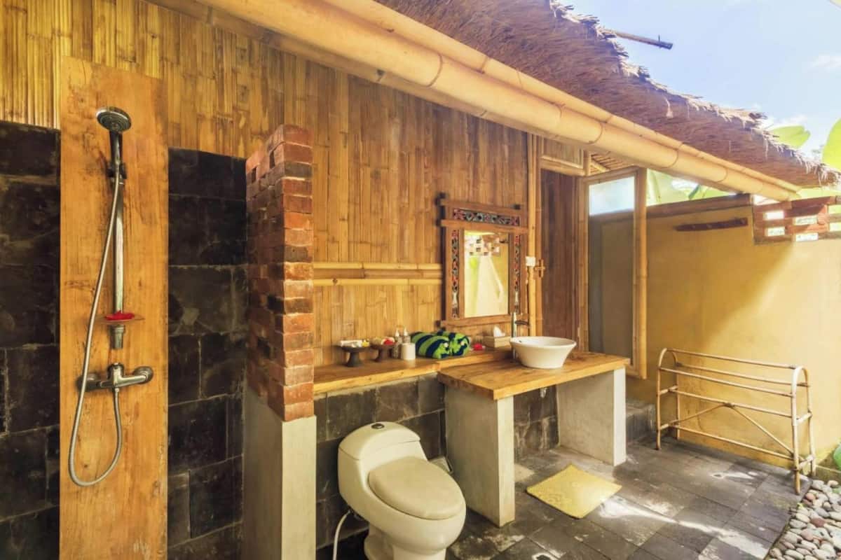 A bathroom with a wooden wall, a shower, a toilet, and a sink.