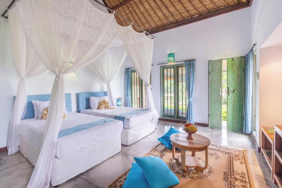 A bedroom with two beds, a wooden table, and a green door.