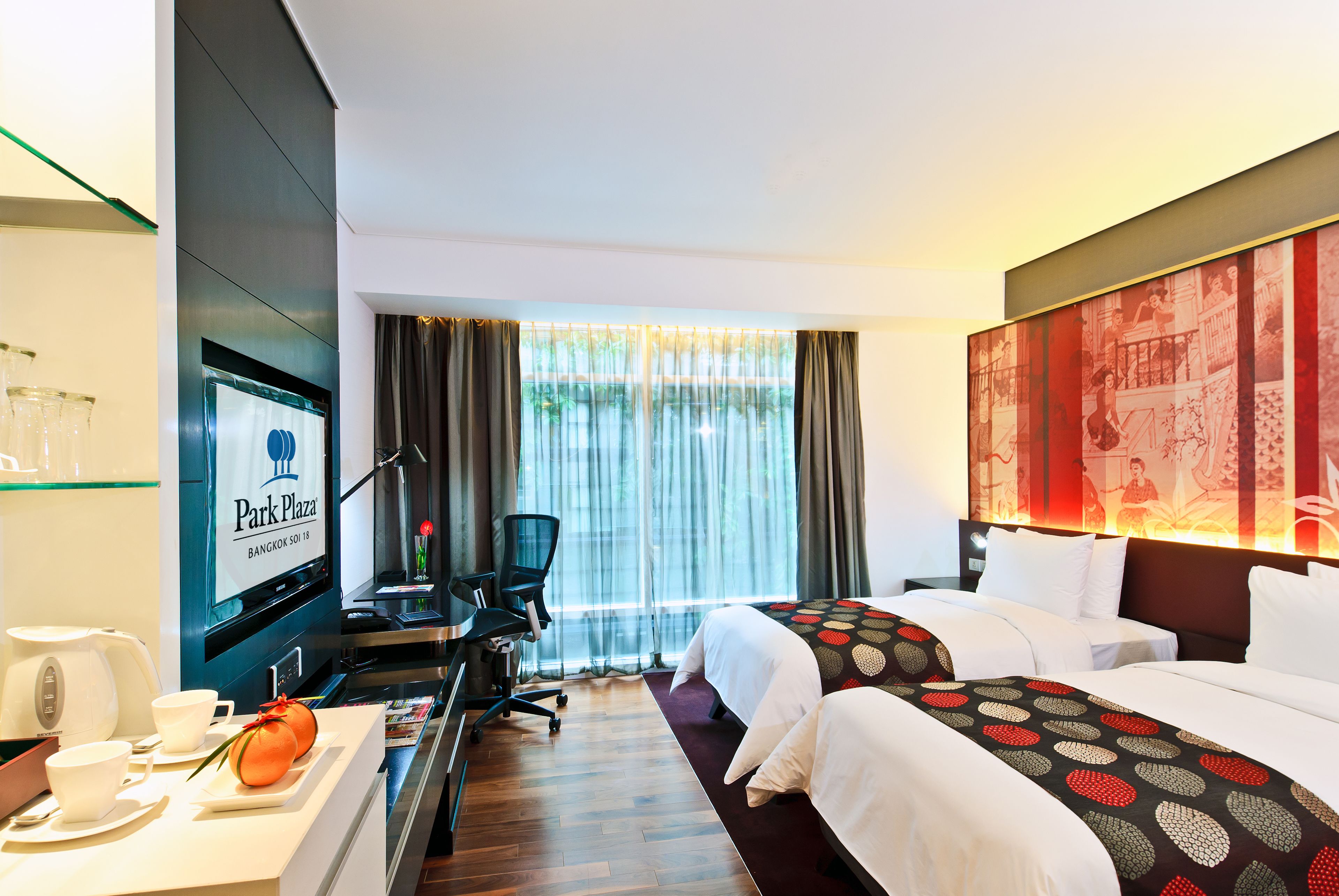 Habitación de hotel con escritorio, dos camas, televisor y un ventanal grande con cortinas.