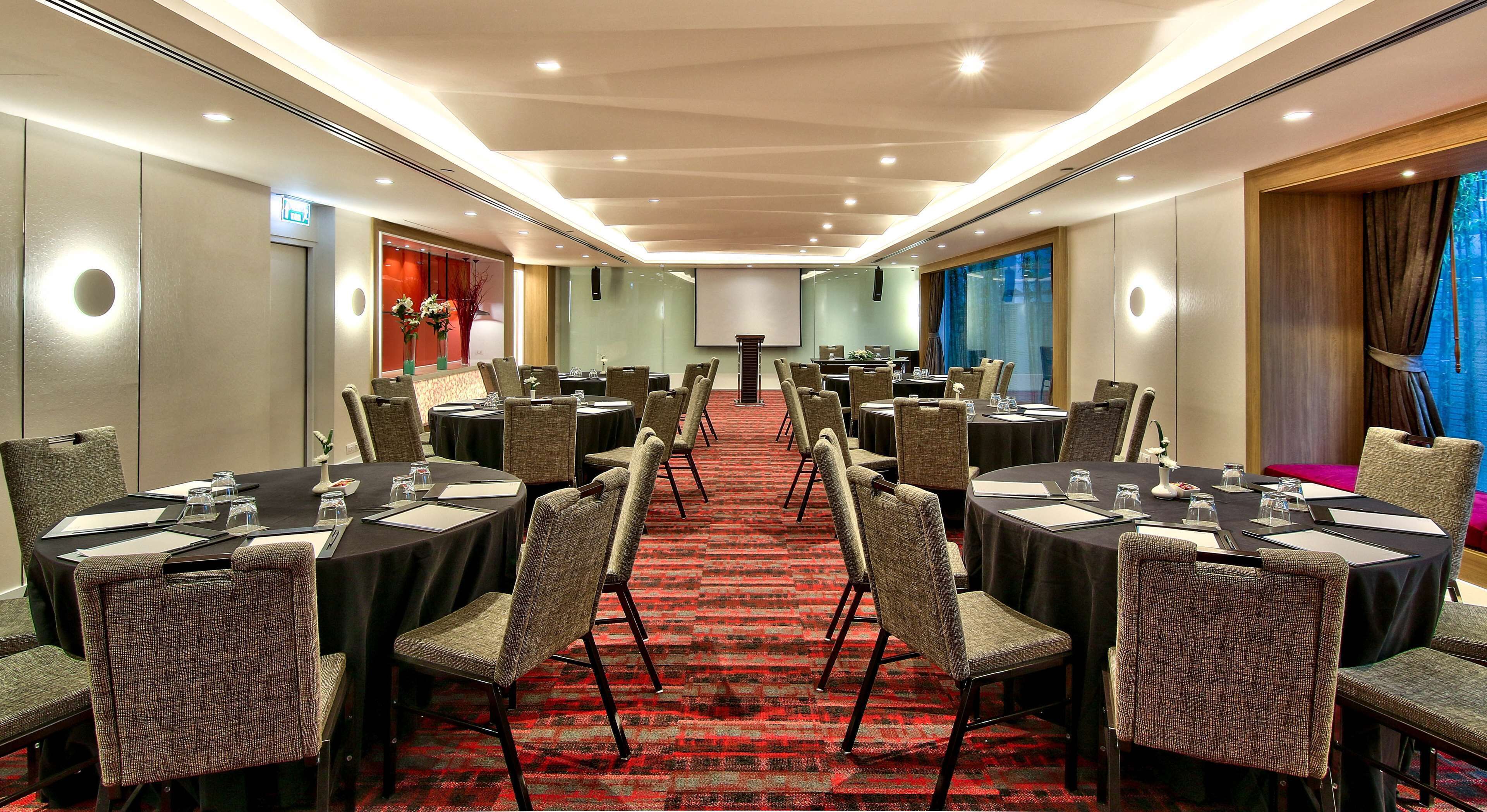 A conference room with round tables, chairs, and a red carpet.