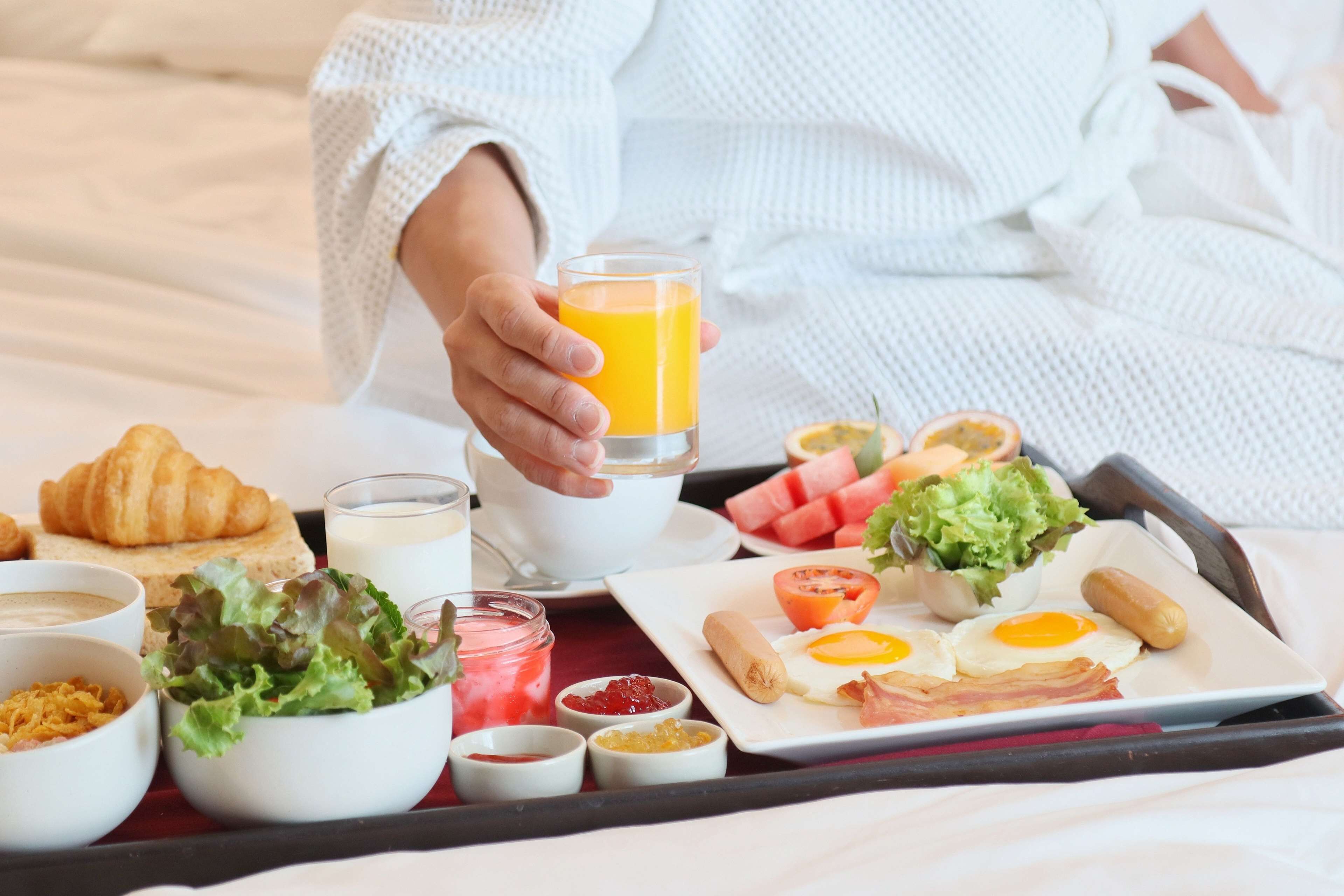 A breakfast tray with croissants, eggs, bacon, and juice.
