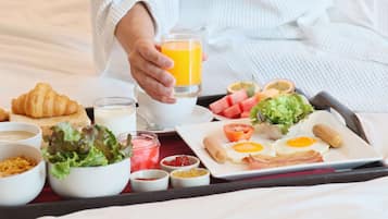 A breakfast tray with croissants, eggs, bacon, and juice.