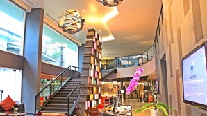 A modern lobby with a staircase, a reception desk, and a large screen displaying information. - PARK PLAZA BANGKOK SOI 18 (Bangkok)