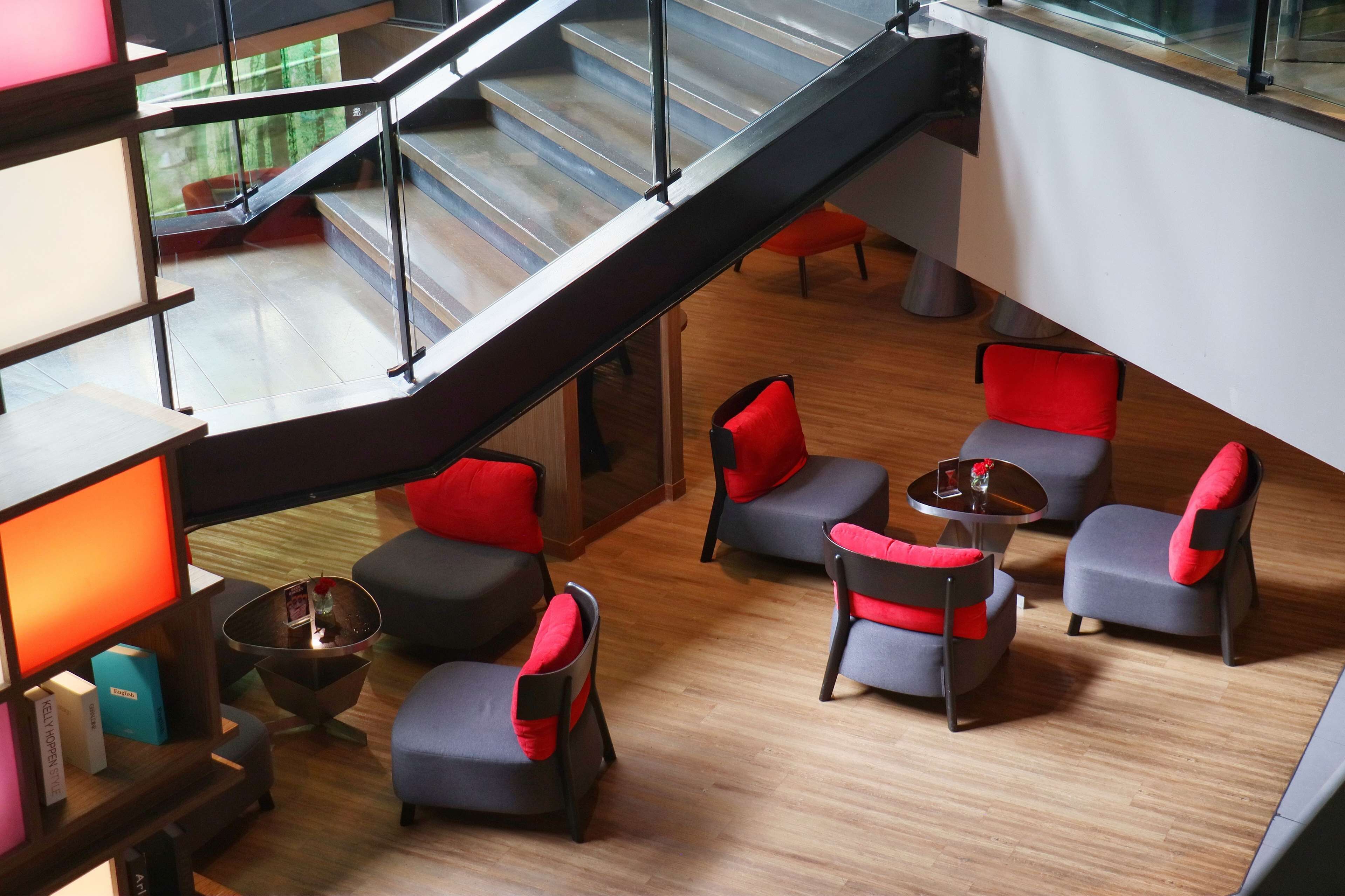 A modern lounge area with a staircase, comfortable seating, and a glass railing.