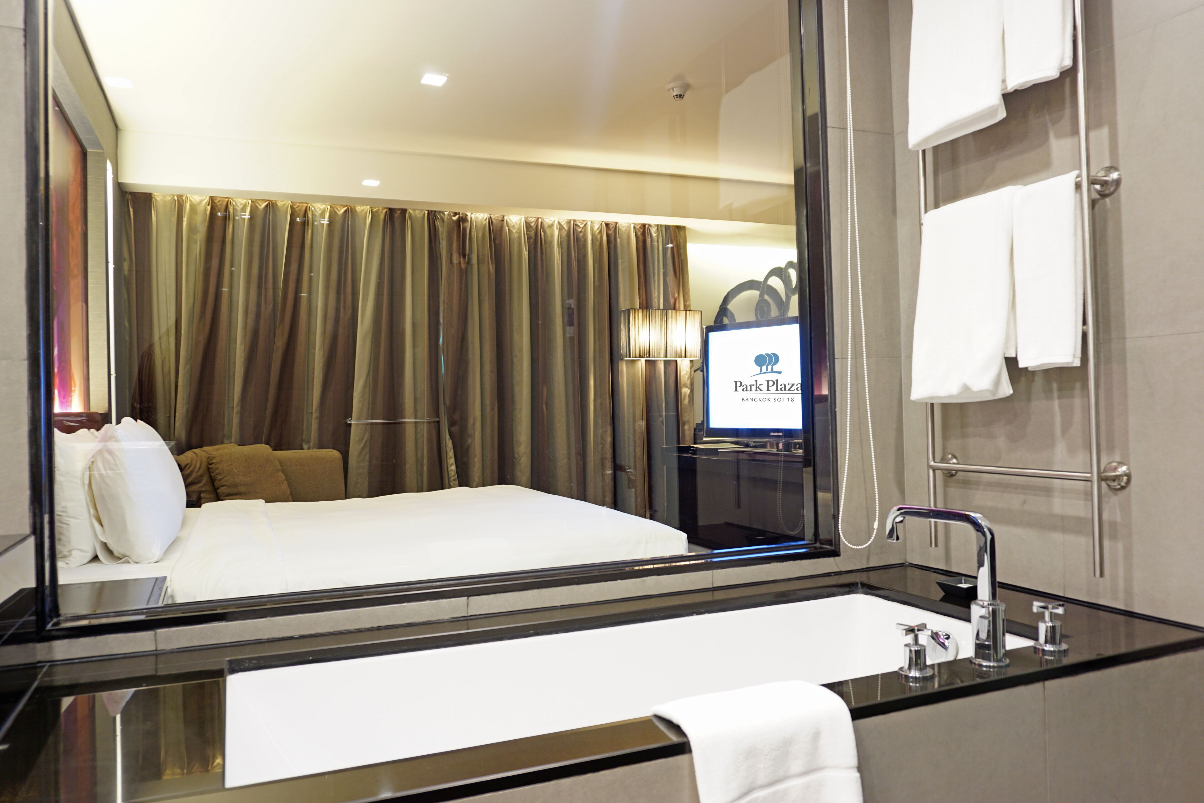 A hotel room with a large bed, a bathroom with a glass-enclosed shower, and a sign for Park Plaza.