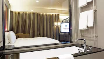Habitación de hotel con una cama grande, un baño con ducha de vidrio y un cartel de Park Plaza.