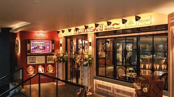 A restaurant interior with a bar, framed pictures, and a staircase.