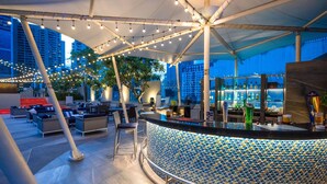 An outdoor bar area with seating, a bar counter, and a city view. - PARK PLAZA BANGKOK SOI 18 (Bangkok)